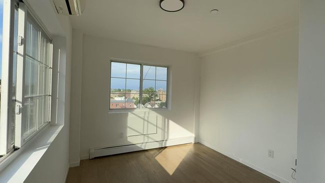 Spare room featuring a baseboard radiator and wood finished floors | Image 6