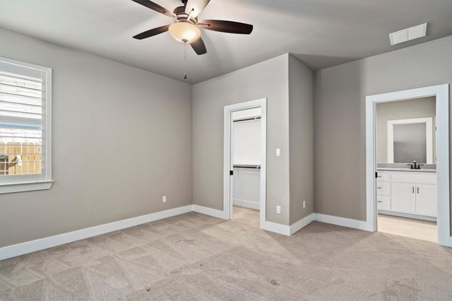Unfurnished bedroom with light colored carpet, a walk in closet, ensuite bath, and a ceiling fan | Image 24