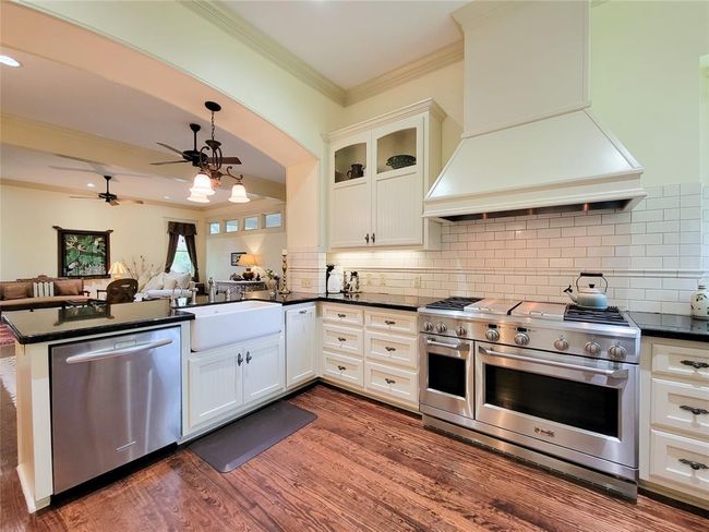Experience a modern kitchen with custom cabinetry, granite countertops, stainless steel appliances, and a spacious peninsula seamlessly connecting to the living area. | Image 16