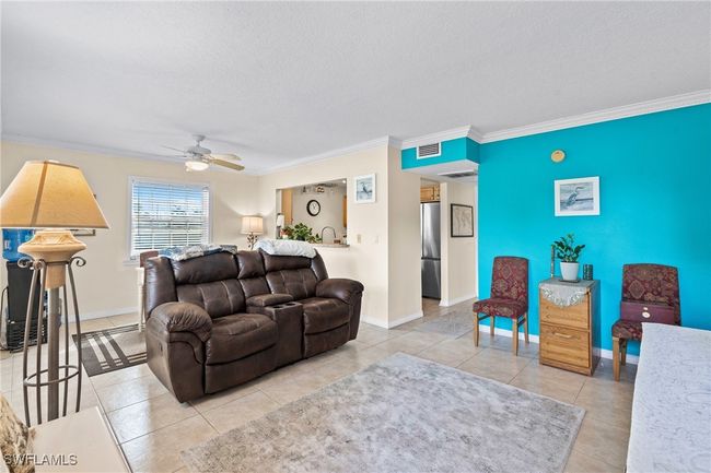 Tiled living room with baseboards, crown molding, an accent wall, and a ceiling fan | Image 5
