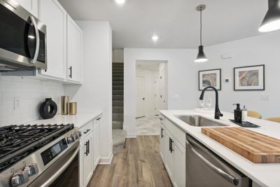 (*Photo of decorated model, actual homes colors and finishes will vary) The kitchen is home to a large center island complete with quartz countertops, stainless appliances, and a luxurious gas cooktop. | Image 1