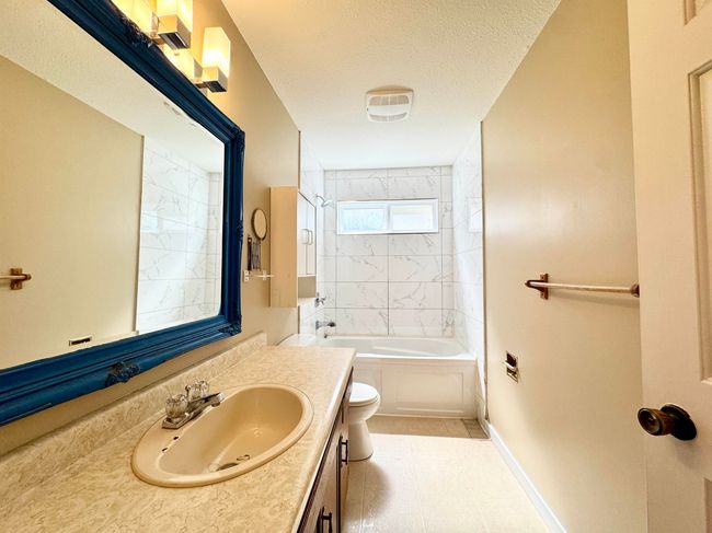 Bathroom with vanity, a textured ceiling, washtub / shower combination, and tile patterned floors | Image 14