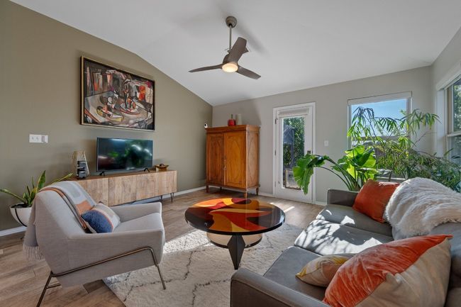 Living area featuring baseboards, light wood finished floors, vaulted ceiling, and a ceiling fan | Image 7