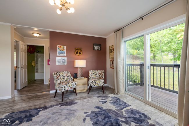 living area with crown molding, baseboards, wood finished floors, and a chandelier | Image 11