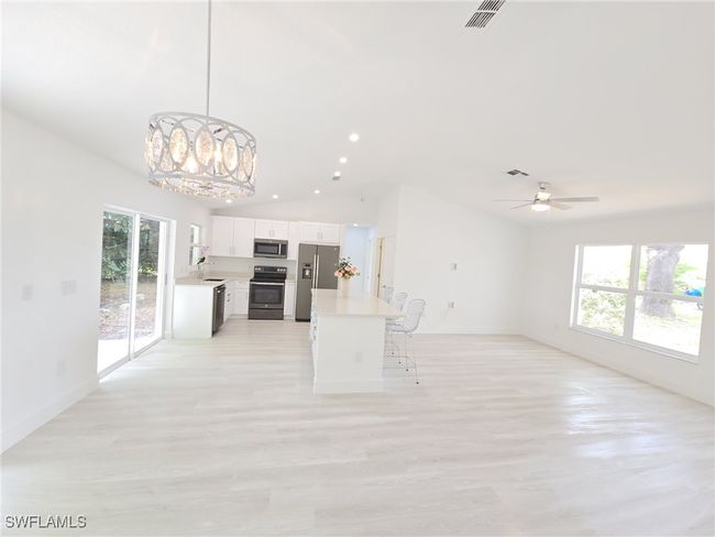 Kitchen with appliances with stainless steel finishes, open floor plan, vaulted ceiling, a chandelier, and light countertops | Image 12