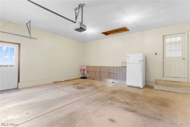 Garage featuring white refrigerator and a garage door opener | Image 25