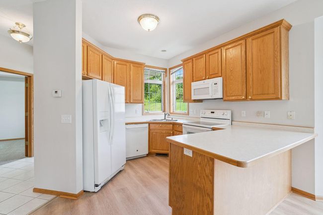 Open concept kitchen with custom 42" oak cabinets, brand new luxury vinyl plank flooring, kitchen window to bring in the sunlight. | Image 8