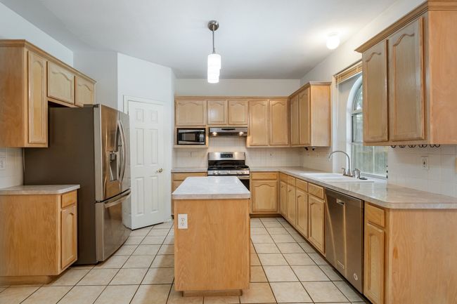 Kitchen with a sink, appliances with stainless steel finishes, exhaust hood, and light brown cabinets | Image 38