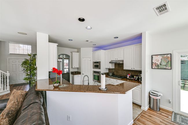 Kitchen with white cabinetry, tasteful backsplash, plenty of natural light, and kitchen peninsula | Image 24
