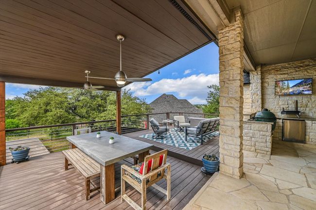 Enjoy a lovely meal on the covered backyard deck, cooled by ceiling fans while overlooking the expansive yard and private greenspace. | Image 28