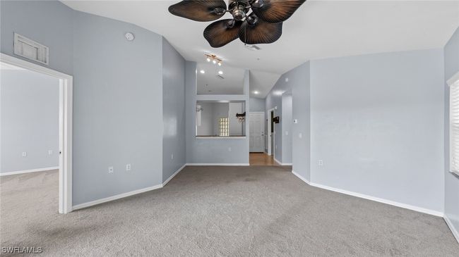 Unfurnished living room with visible vents, ceiling fan, carpet, and vaulted ceiling | Image 8