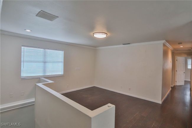 Empty room with ornamental molding, dark wood finished floors, baseboards, and recessed lighting | Image 18