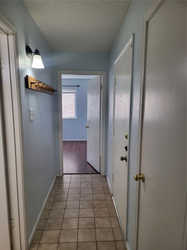 Hallway featuring baseboards, a textured ceiling, and light tile patterned flooring | Image 9