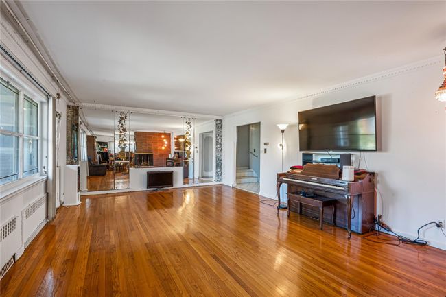Unfurnished living room with wood-type flooring, radiator heating unit, and an inviting chandelier | Image 12