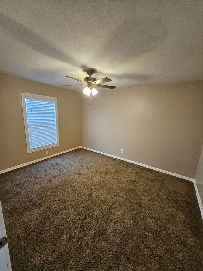 Unfurnished room featuring baseboards, a textured ceiling, ceiling fan, and dark carpet | Image 9