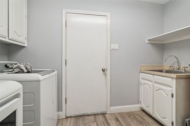 Laundry area featuring washing machine and dryer, light wood-type flooring, and cabinet space | Image 22