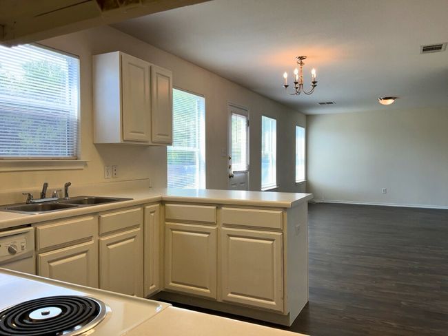 Kitchen featuring light countertops, white cabinetry, a chandelier, dark wood-type flooring, and a peninsula | Image 6