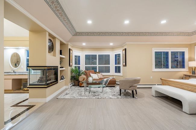 Living room with baseboard heating, crown molding, a multi sided fireplace, recessed lighting, and wood finished floors | Image 20