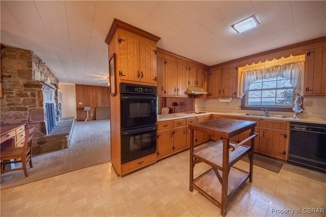 Kitchen with sink, a stone fireplace, black appliances, and light colored carpet | Image 13