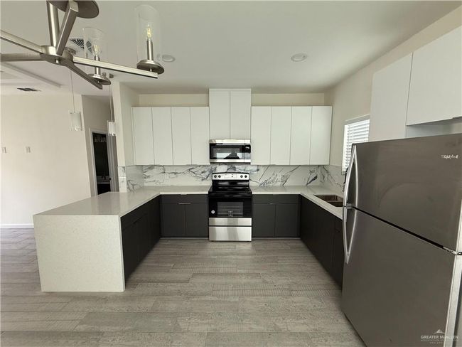 Kitchen with stainless steel appliances, a peninsula, modern cabinets, and backsplash | Image 4