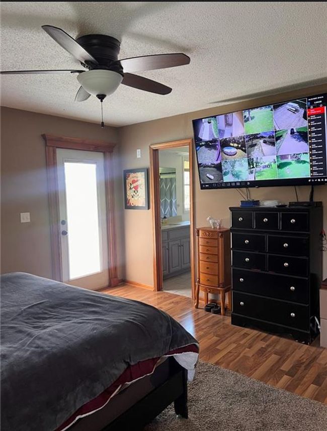 Bedroom featuring wood finished floors, connected bathroom, a textured ceiling, and a ceiling fan | Image 10
