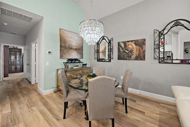 Dining room with wood finished floors, baseboards, a chandelier, and lofted ceiling | Image 6