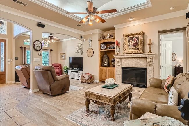 Living room with arched walkways, visible vents, a tile fireplace, and ornamental molding | Image 8