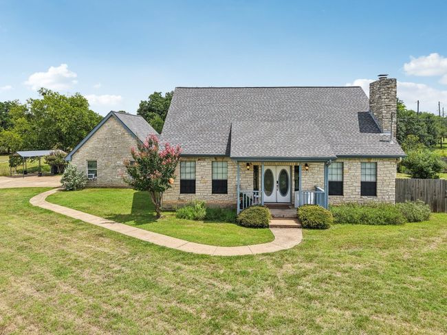 View of front of home with stone siding, a chimney, roof with shingles, covered porch, and a detached carport | Image 34