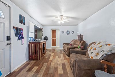 Living room with a textured ceiling, hardwood / wood-style flooring, and ceiling fan | Image 2