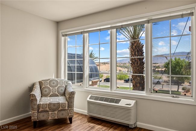 Living area with wood finished floors, a wall mounted air conditioner, and baseboards | Image 11
