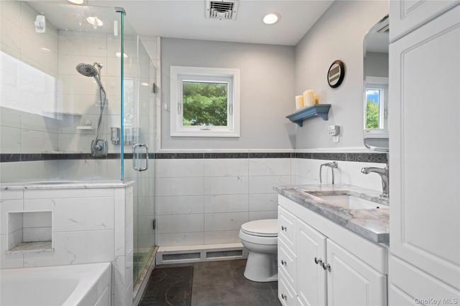 Full bathroom featuring vanity, a stall shower, tile walls, a wainscoted wall, and a garden tub | Image 15
