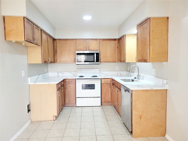 Kitchen featuring sink, light tile patterned flooring, and stainless steel appliances | Image 4