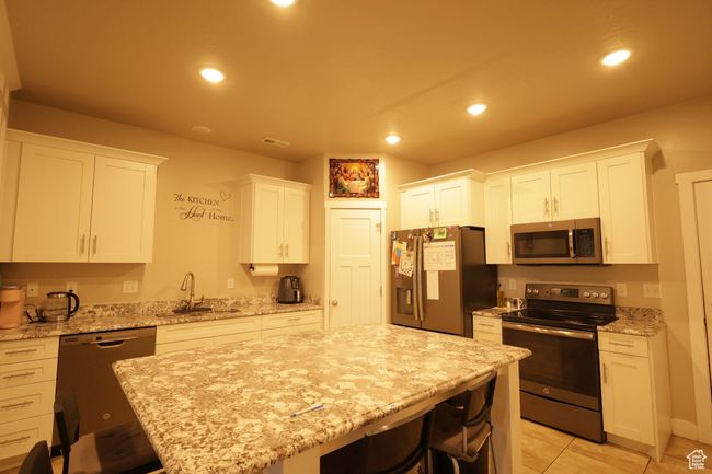 Kitchen featuring stainless steel appliances, a breakfast bar, white cabinetry, and recessed lighting | Image 4
