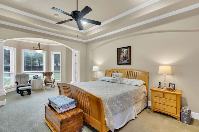 Bedroom with ornate columns, carpet, arched walkways, ornamental molding, and a tray ceiling | Image 21