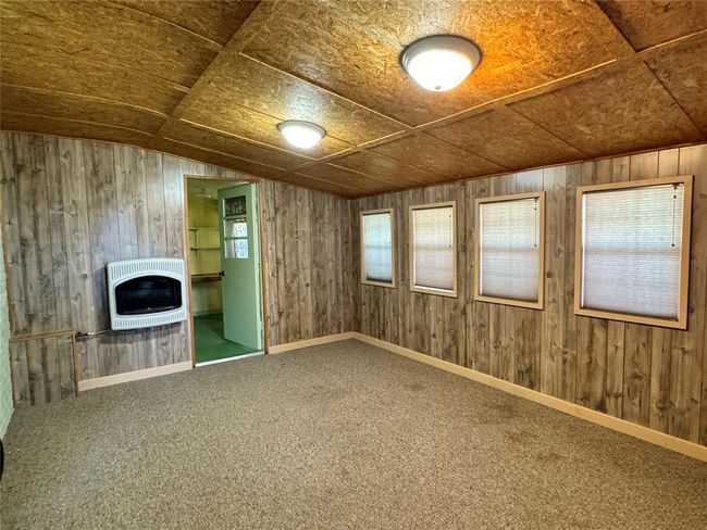 Unfurnished living room featuring wooden walls and carpet | Image 14