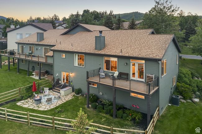 Back of property with a patio, a fenced backyard, a fire pit, a chimney, and roof with shingles | Image 47
