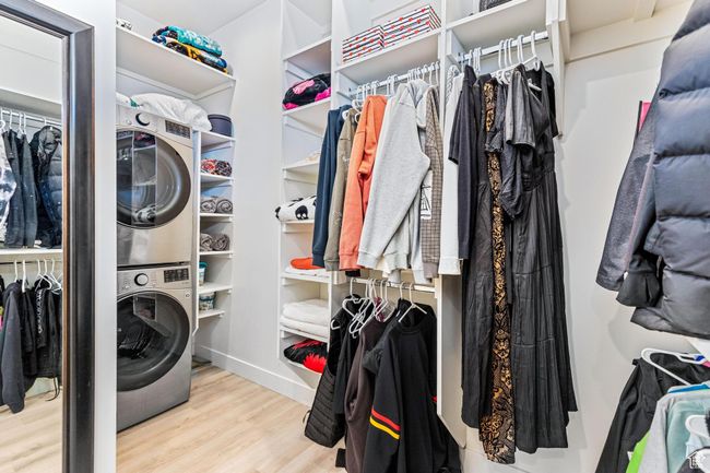 Spacious closet with stacked washer and dryer and wood finished floors | Image 27