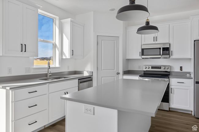 Kitchen with a sink, dark wood-style flooring, stainless steel appliances, a center island, and white cabinetry | Image 7