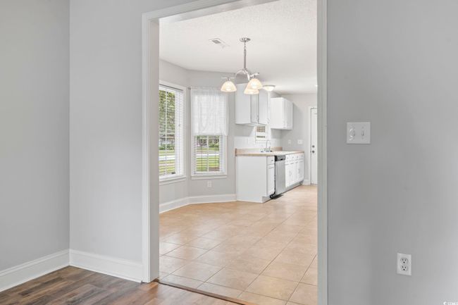 Kitchen featuring stainless steel dishwasher, a chandelier, a sink, white cabinetry, and light countertops | Image 8