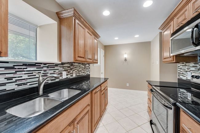 Kitchen with tasteful backsplash, baseboards, dark stone countertops, appliances with stainless steel finishes, and a sink | Image 14