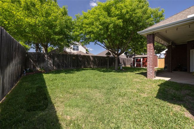 View of yard featuring a fenced backyard, an outdoor structure, a patio, and a shed | Image 35