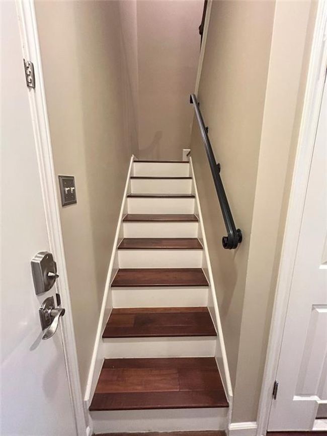 The wood from the living space is carried through the back hall and up the stairs. The stairs have wrought iron balusters with walnut handrailing. There is no carpet in this unit. | Image 28