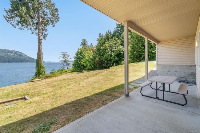 View of green lawn with a water and mountain view and a patio area | Image 54