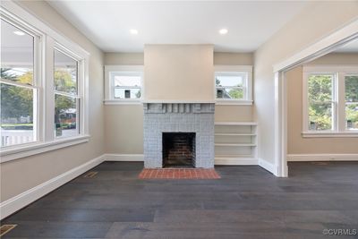 Unfurnished living room with dark hardwood / wood-style flooring and a brick fireplace | Image 3