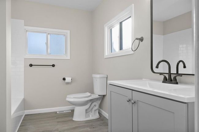 Bathroom with vanity, baseboards, wood finished floors, toilet, and shower / tub combination | Image 13