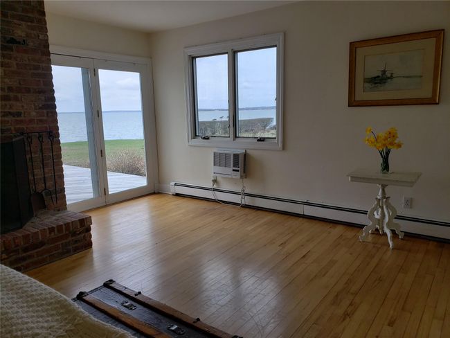 Unfurnished living room with a water view, an AC wall unit, and light wood finished floors | Image 22