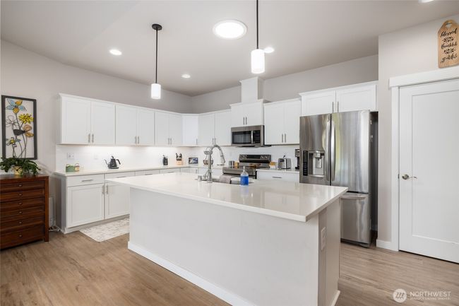 There are upgraded white cabinets in this spacious kitchen w/under cabinet lighting, quartz countertops, electric range and pantry! | Image 13