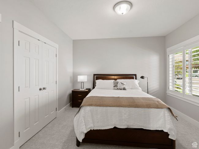 Main floor bedroom with light colored carpet, baseboards, and a closet | Image 12