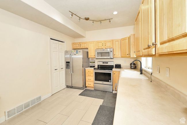 Kitchen with visible vents, appliances with stainless steel finishes, light countertops, a sink, and light brown cabinets | Image 6