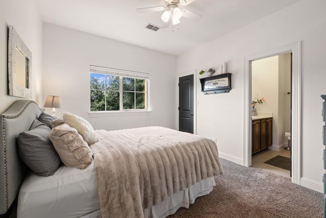 Bedroom with ceiling fan, light colored carpet, baseboards, ensuite bathroom, and visible vents | Image 35